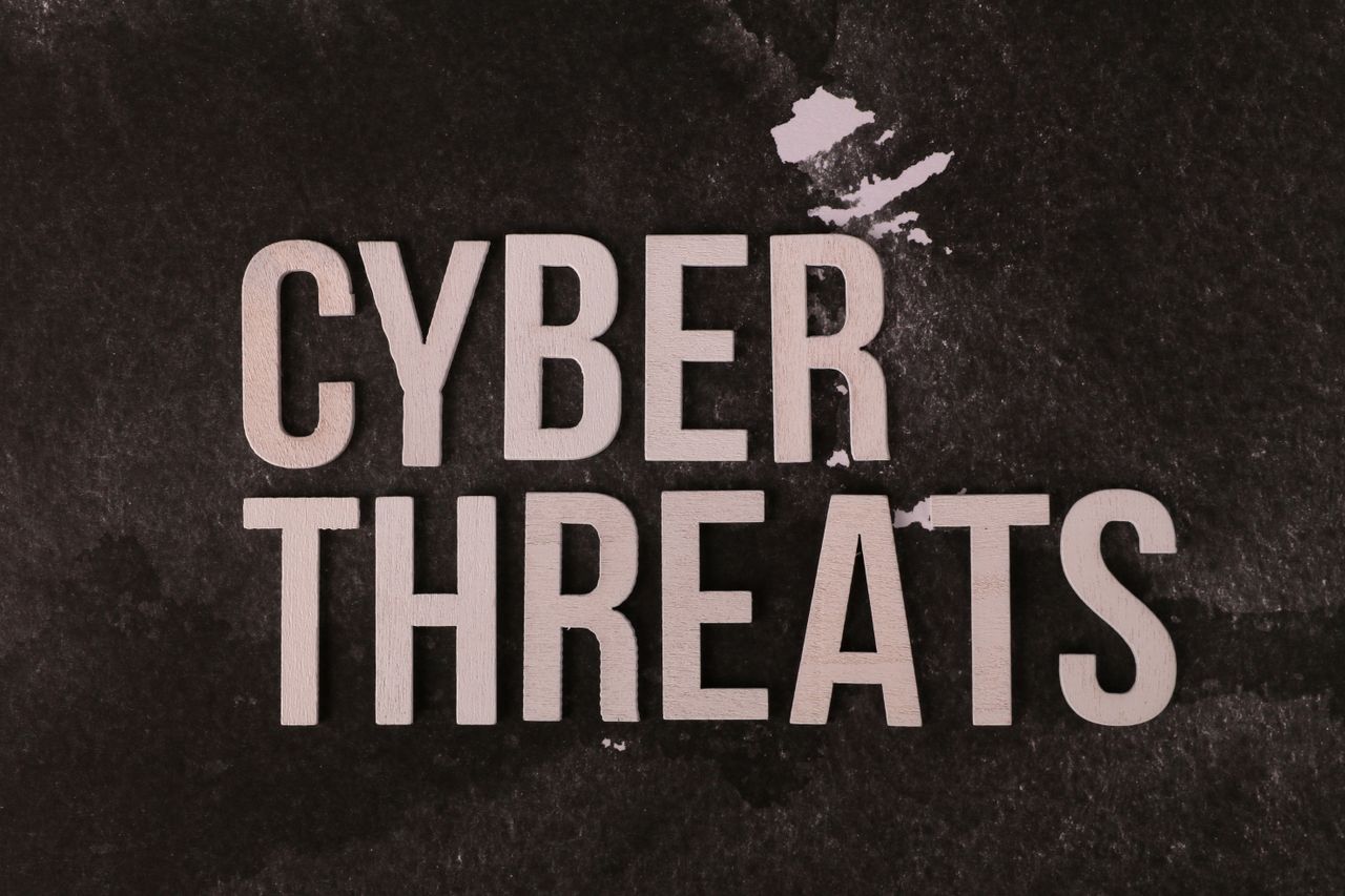 The phrase 'Cyber Threats' displayed on a textured dark background, emphasizing digital security.